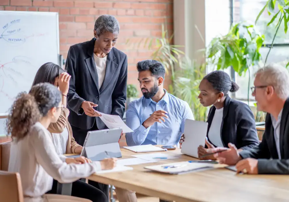 diverse business people sitting at table in a meeting with laptops and paperwork